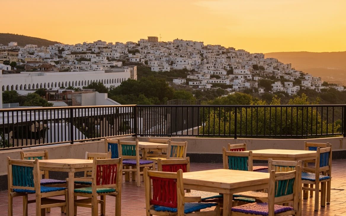 La terrasse de Diyar Timnay au coucher du soleil, la ville blanche de Moulay Idriss étagée sur la colline du Zerhoun.